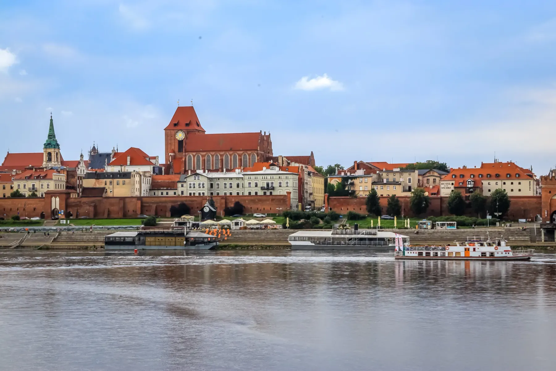Panoramablick auf die Altstadt von Toruń von der Weichsel mit Backsteinkirchen, historischen Gebäuden und Booten unter bew...