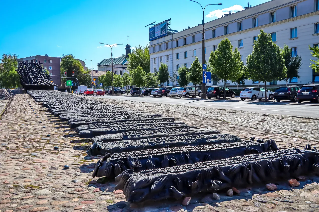 Pomnik Poległym i Pomordowanym na Wschodzie w Warszawie, z ciemnymi, rzeźbionymi formami przypominającymi podkłady kolejow...
