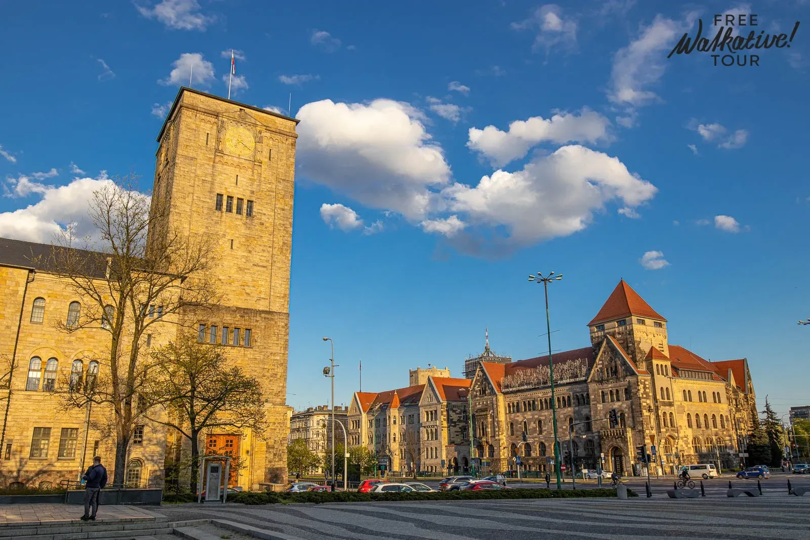 Zamek Cesarski w Poznaniu z wysoką wieżą zegarową po lewej i głównym budynkiem z czerwonymi dachami po prawej, pod błękitn...