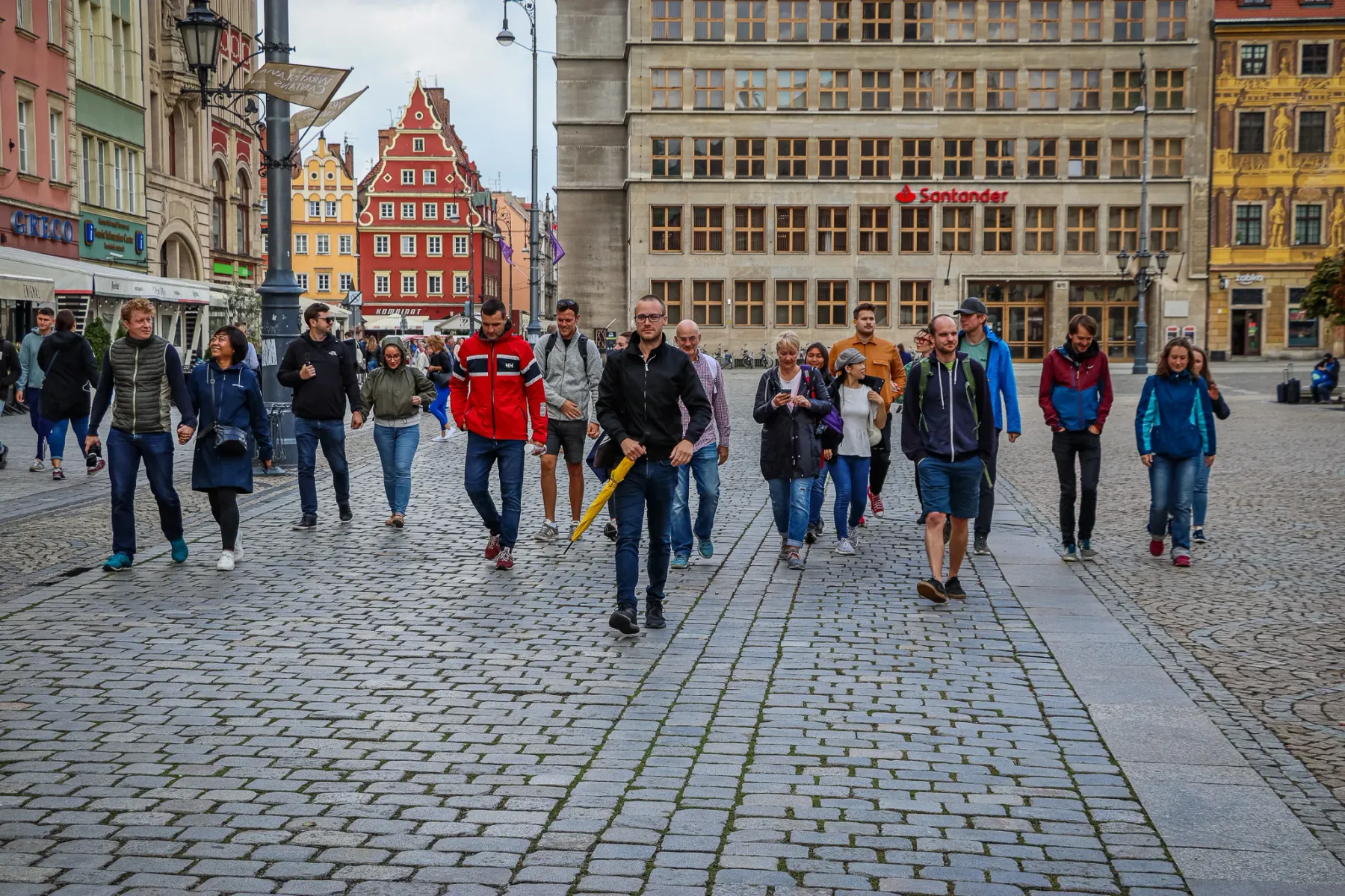 Grupa turystów na pieszej wycieczce po historycznych ulicach Wrocławia.
