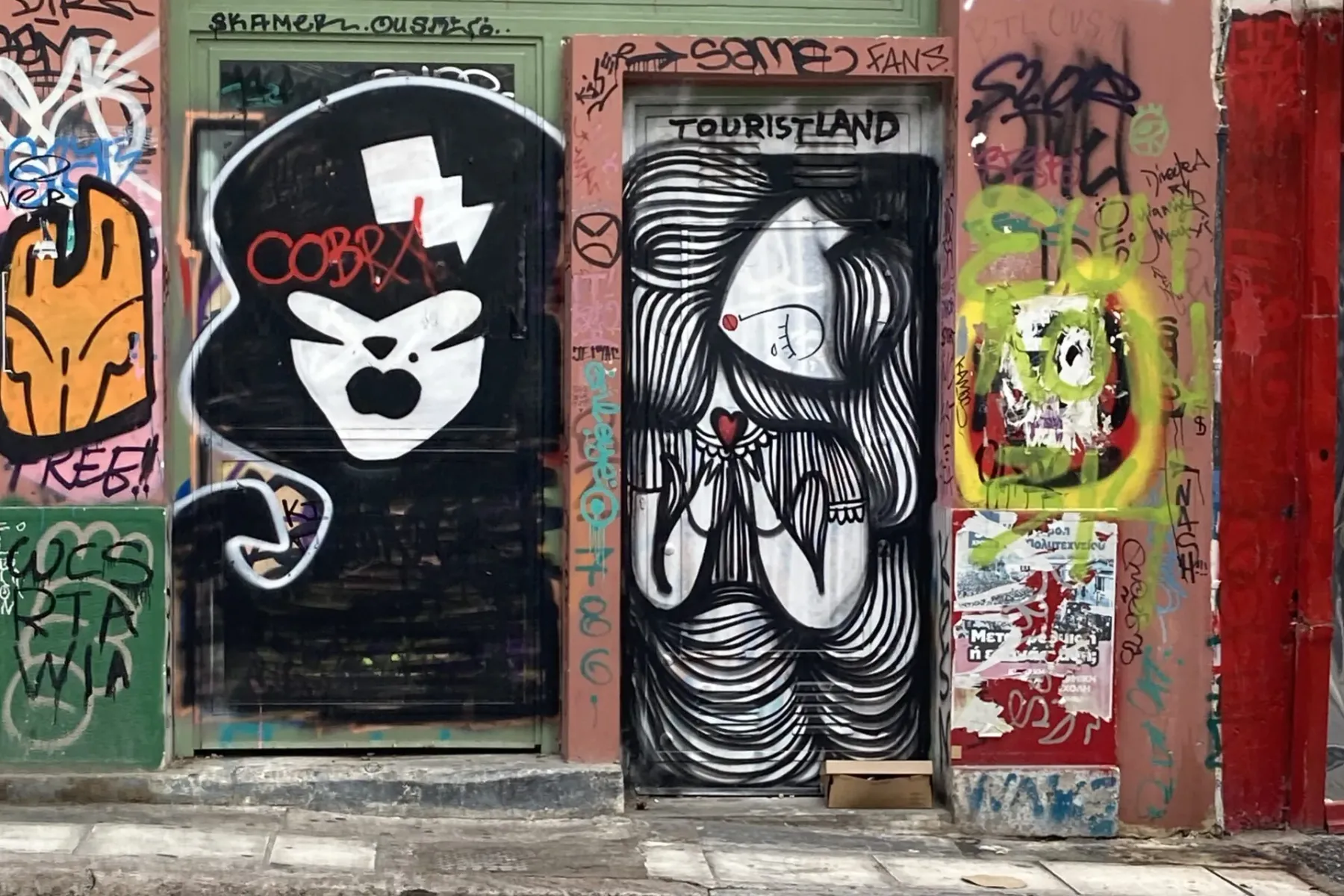 Two urban doors and surrounding walls covered in various street art and graffiti, featuring stylized figures and abstract ...