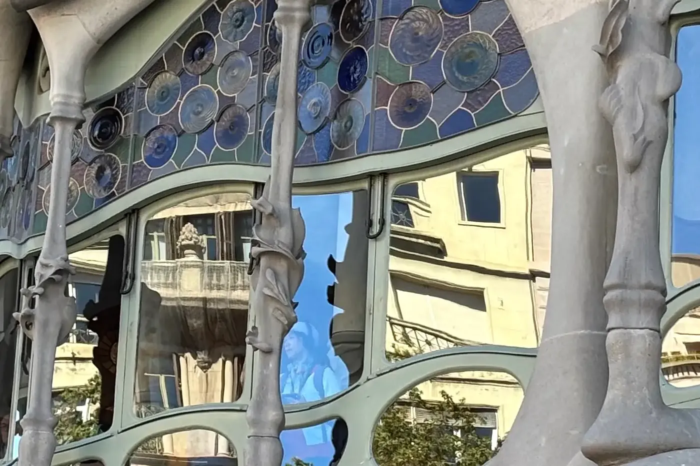 Close-up of Casa Batlló's organic stone balconies and colorful mosaic details under warm light, Barcelona.