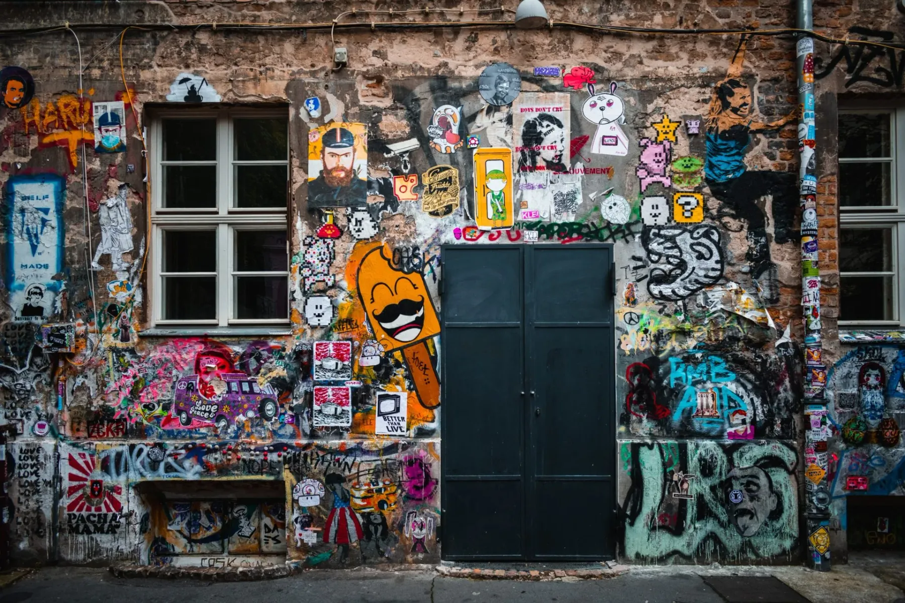 Eine verwitterte Backsteinfassade in Berlin, dicht bedeckt mit bunter Street Art, Graffiti und Aufklebern.