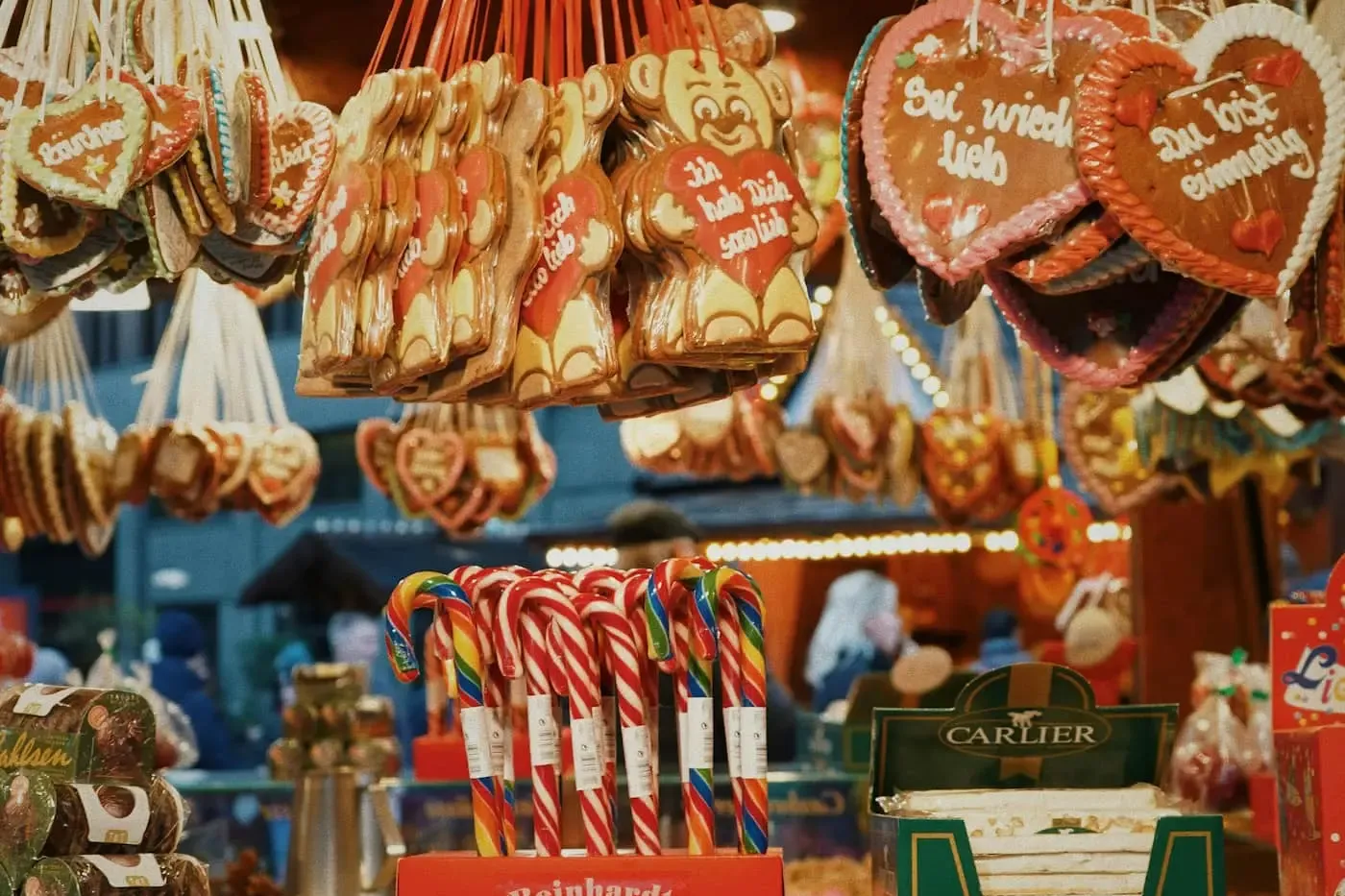 Ein Stand auf einem Weihnachtsmarkt, der Lebkuchenherzen, Zuckerstangen und geröstete Nüsse verkauft.