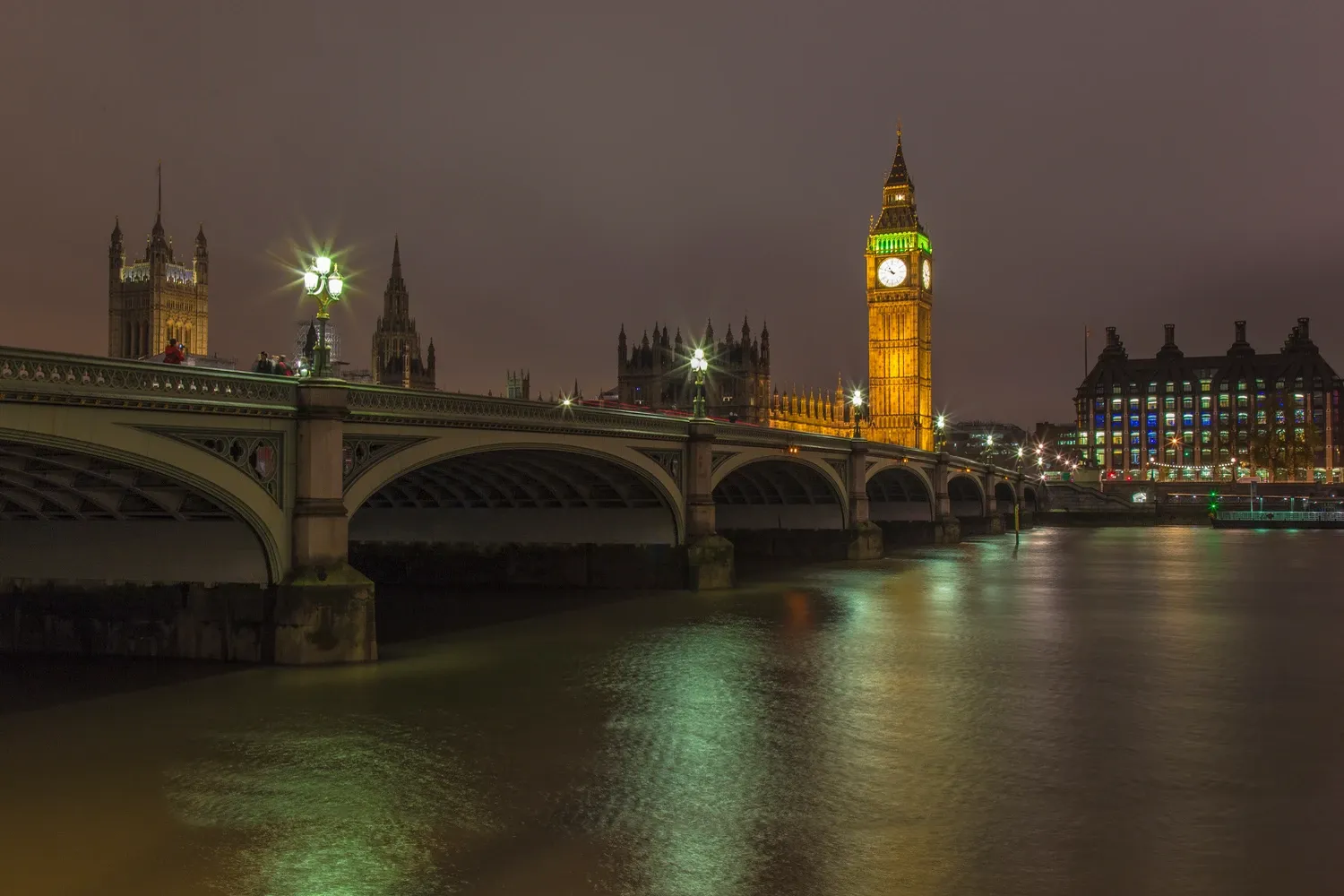 El Big Ben y el Palacio de Westminster iluminados por la noche, vistos sobre el río Támesis con el Puente de Westminster e...