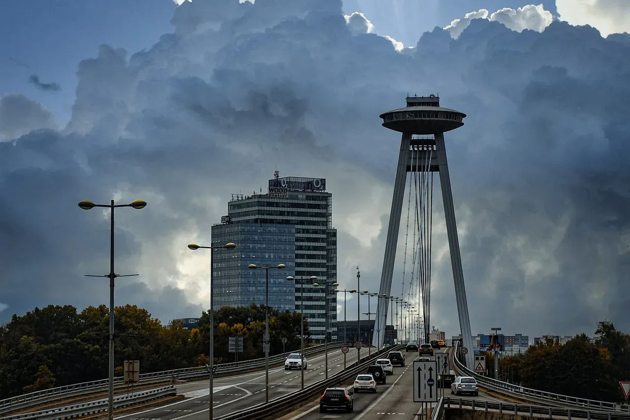 Moderne UFO-Brücke (Most SNP) in Bratislava mit Autos auf der Fahrbahn, einem markanten Untertassen-Restaurant, unter dram...