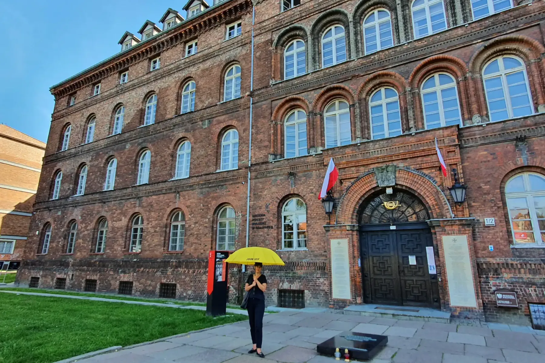 Edificio histórico de ladrillo de la Oficina Postal Polaca en Gdansk con ventanas arqueadas, entrada oscura y banderas pol...
