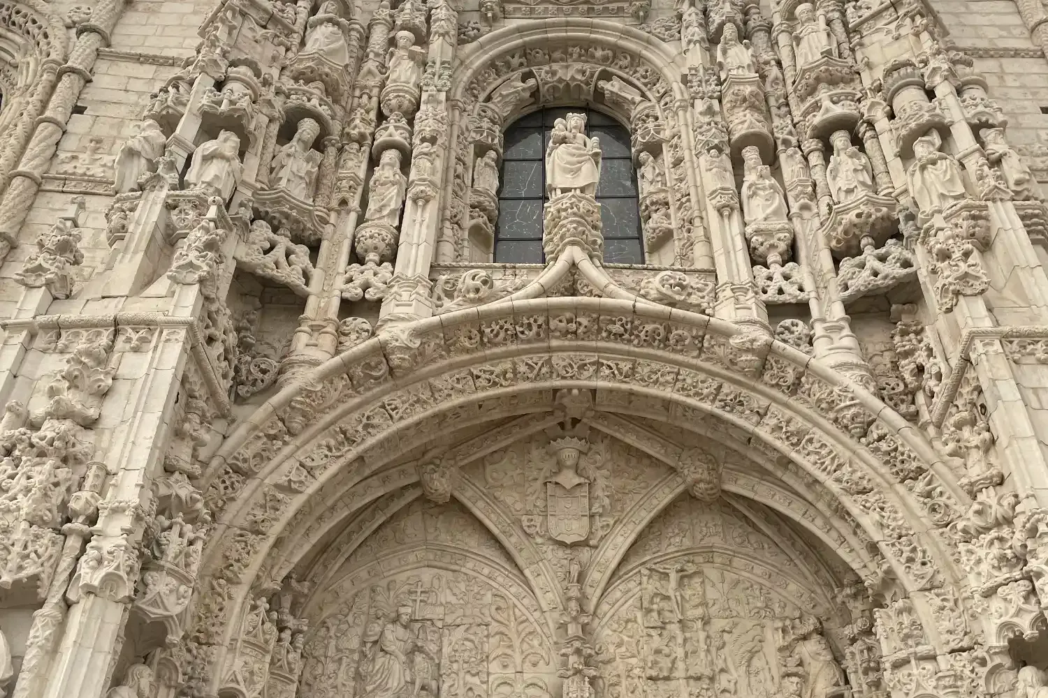 Detailreiche weiße Kalksteinfassade des Jerónimos-Klosters in Lissabon - kunstvolle Skulpturen und Bögen.