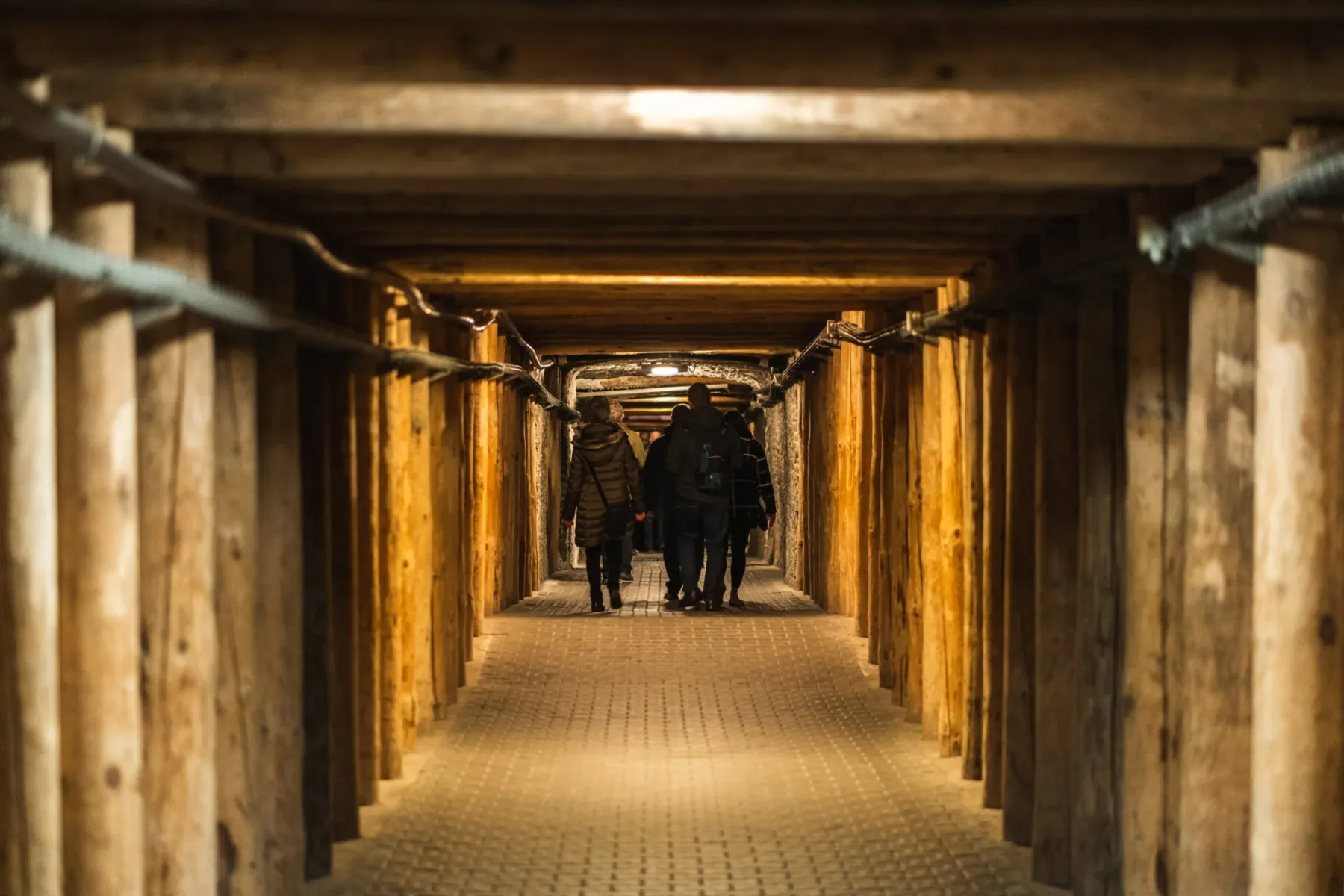 Eine Gruppe von Touristen geht durch einen von Holzbalken gestützten unterirdischen Korridor im Salzbergwerk Wieliczka.