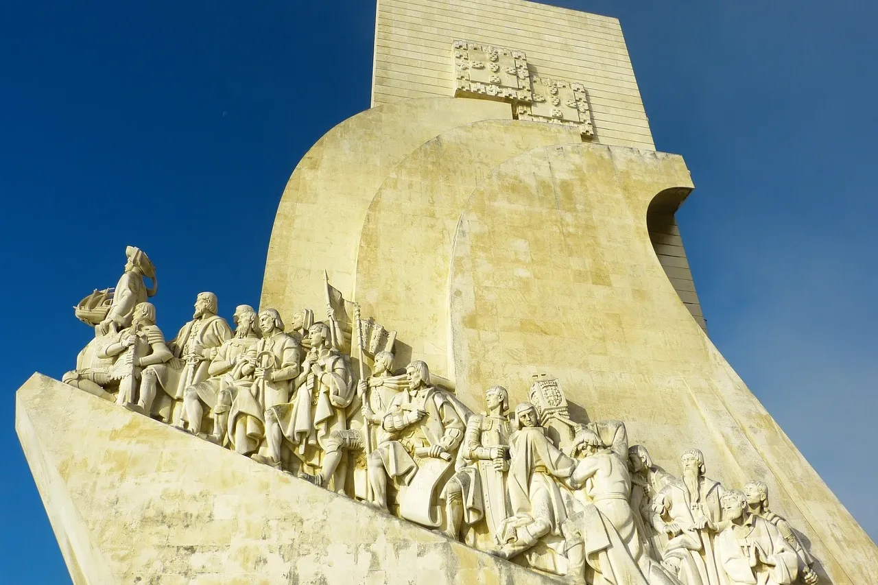 Steingebautes Denkmal der Entdeckungen in Lissabon mit Statuen historischer Seefahrer auf einem Schiffsbug.