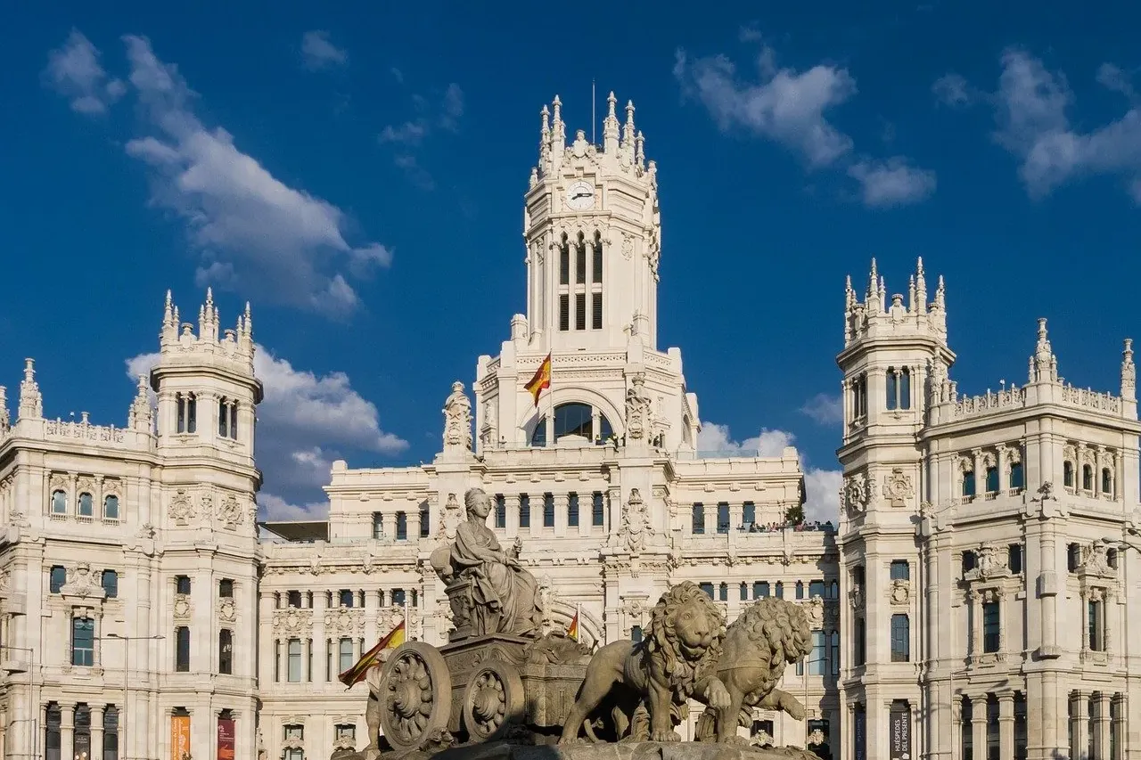 Cibeles Fountain with a seated goddess in a chariot pulled by two lions, in front of the ornate Palacio de Cibeles in Madrid.
