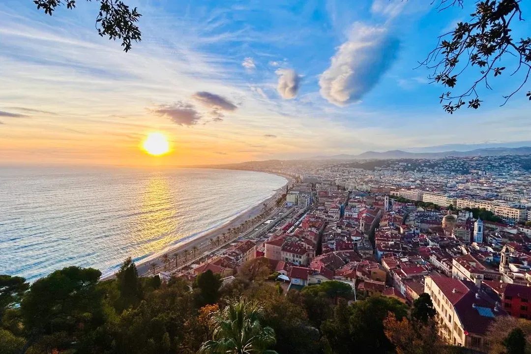 Vista aérea de la costa de Niza al atardcer, con la Promenade des Anglais, el Mar Mediterráneo y edificios de la ciudad.