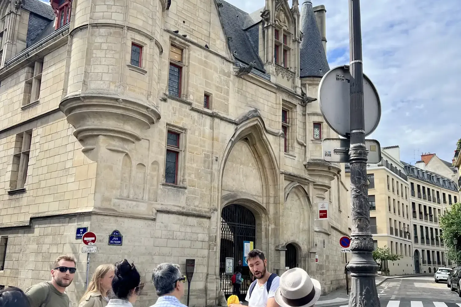 Reiseführer spricht kleine Touristengruppe vor dem historischen Hôtel de Sens in Paris an einem bewölkten Tag an.