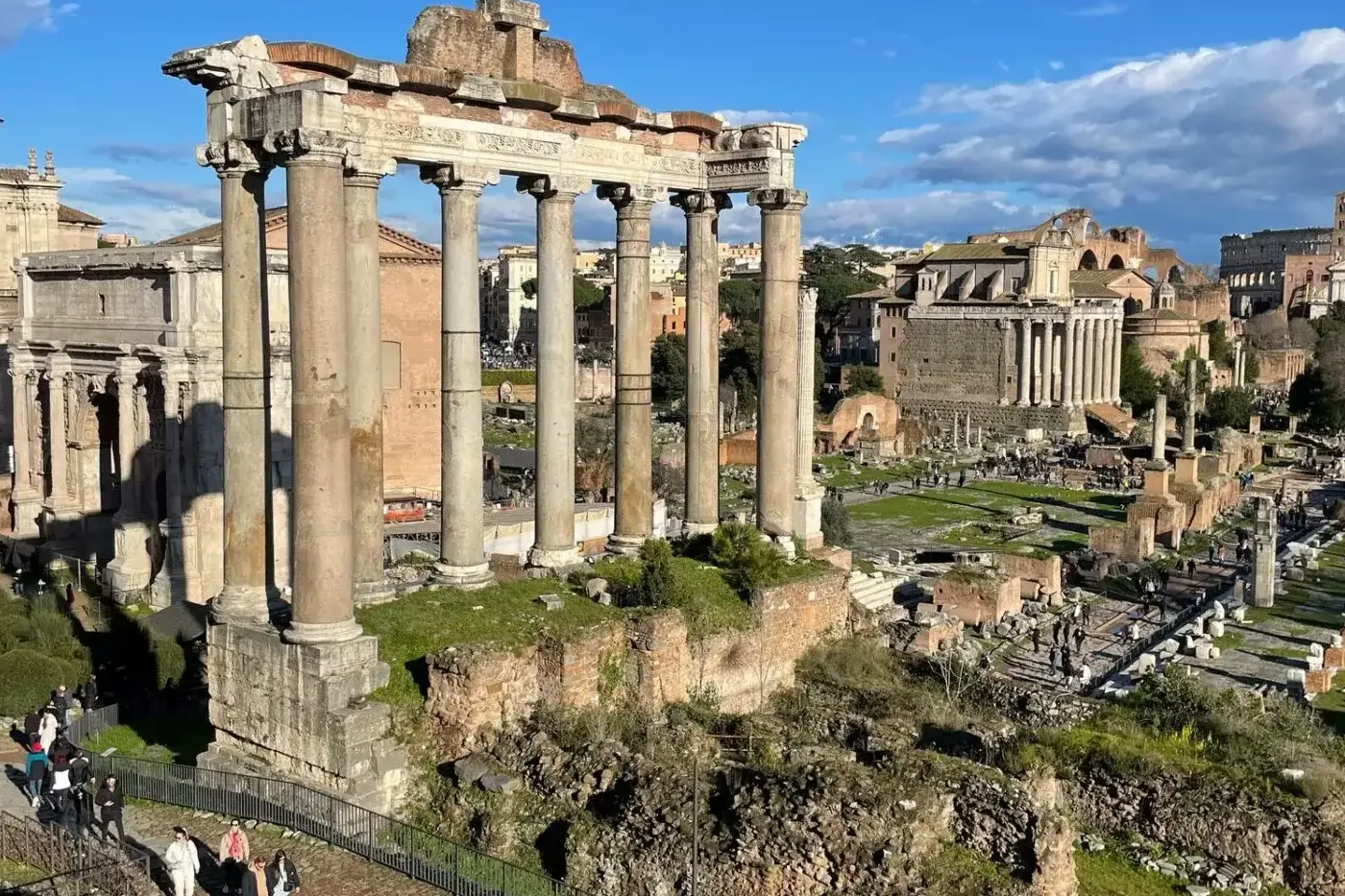 Vista del Foro Romano en Roma, mostrando ruinas antiguas, incluyendo ocho altas columnas del Templo de Saturno bajo un cie...
