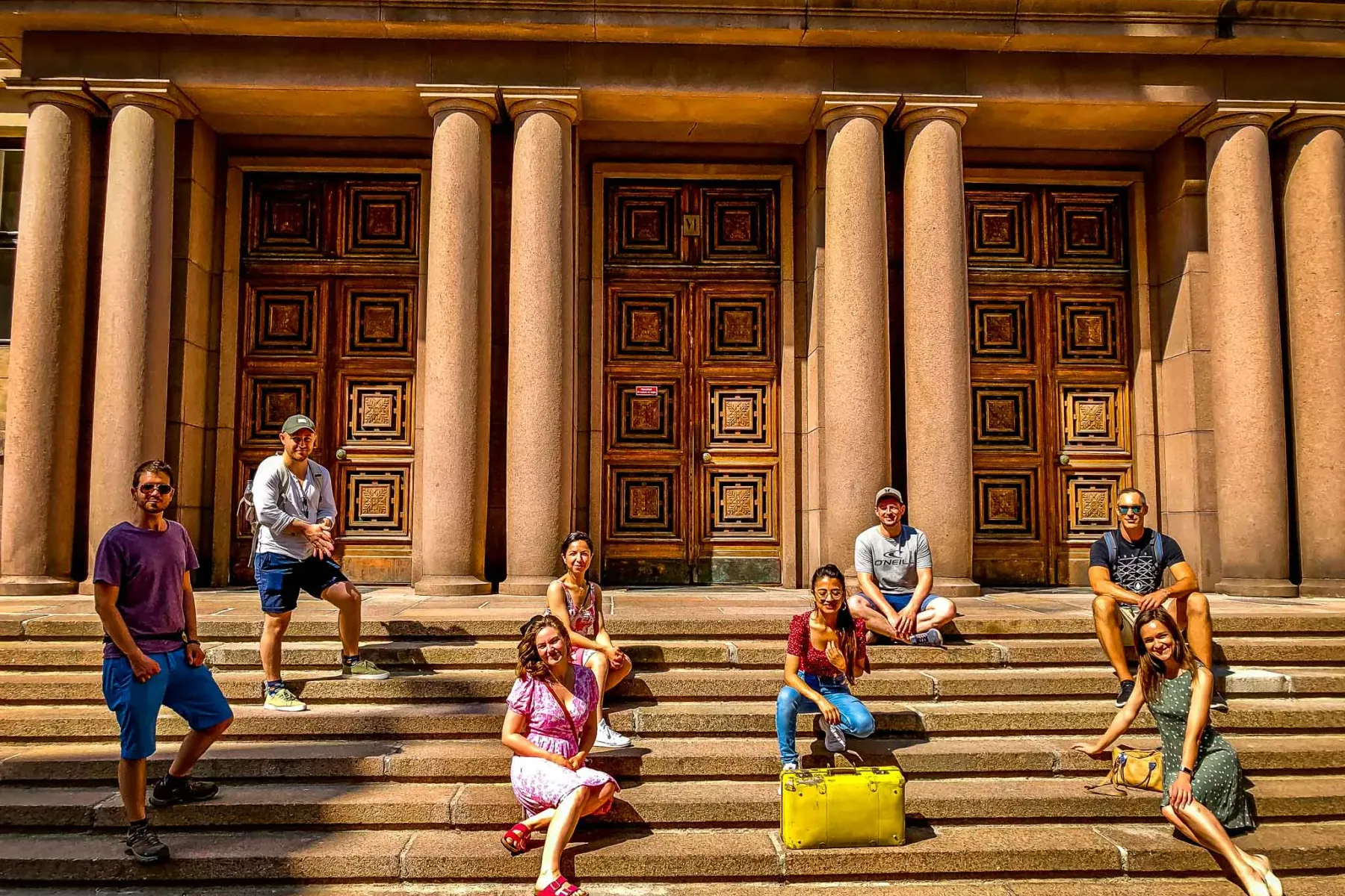 Fröhliche Touristen posieren auf den Stufen eines wunderschönen Gebäudes in Helsinki.