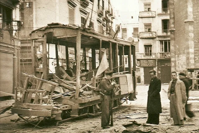 A destroyed tram on a street in Valencia during the Spanish Civil War. Sepia-toned photograph.