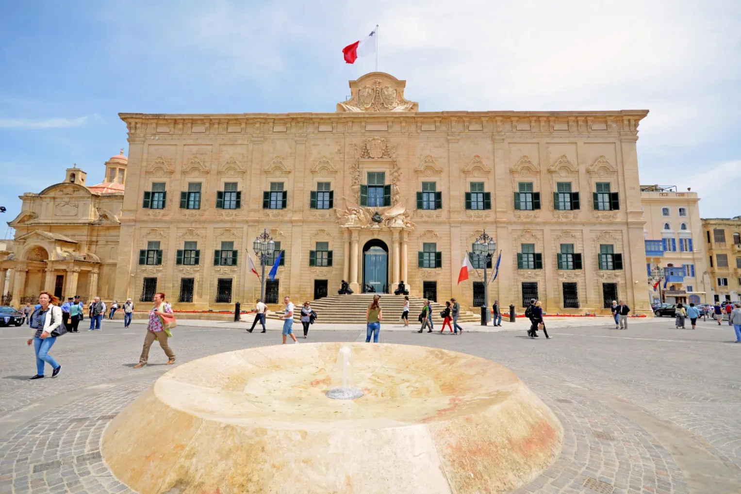 La Auberge de Castille, un edificio barroco adornado con contraventanas verdes y la bandera maltesa, en la Plaza de Castil...