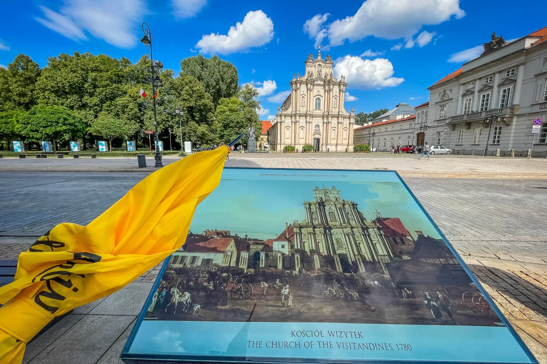 La Iglesia de las Visitandinas en Varsovia, un edificio barroco claro, vista detrás de un panel informativo histórico.