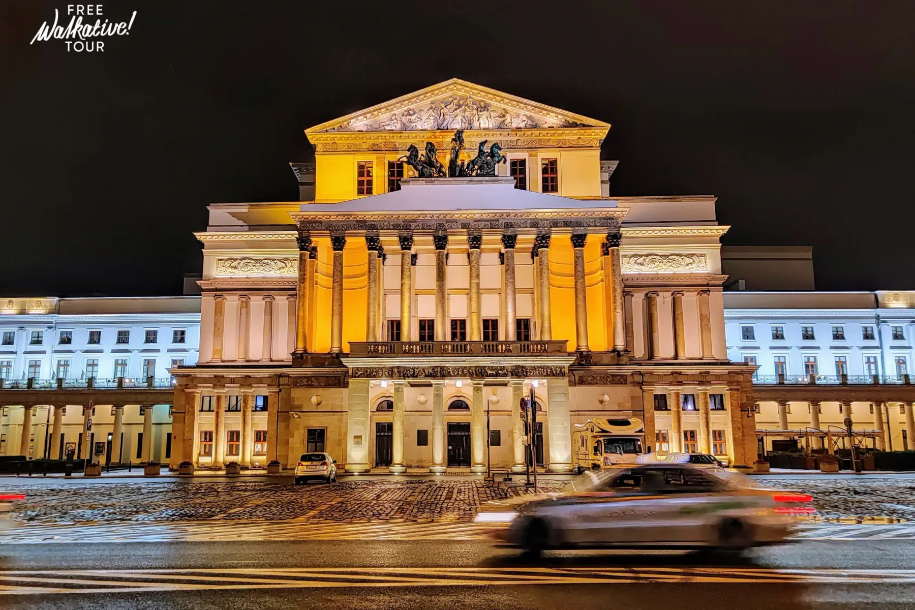 Das Große Theater in Warschau bei Nacht, klassische Fassade mit Säulen und Skulpturen, warm beleuchtet. Schnee auf dem Boden.
