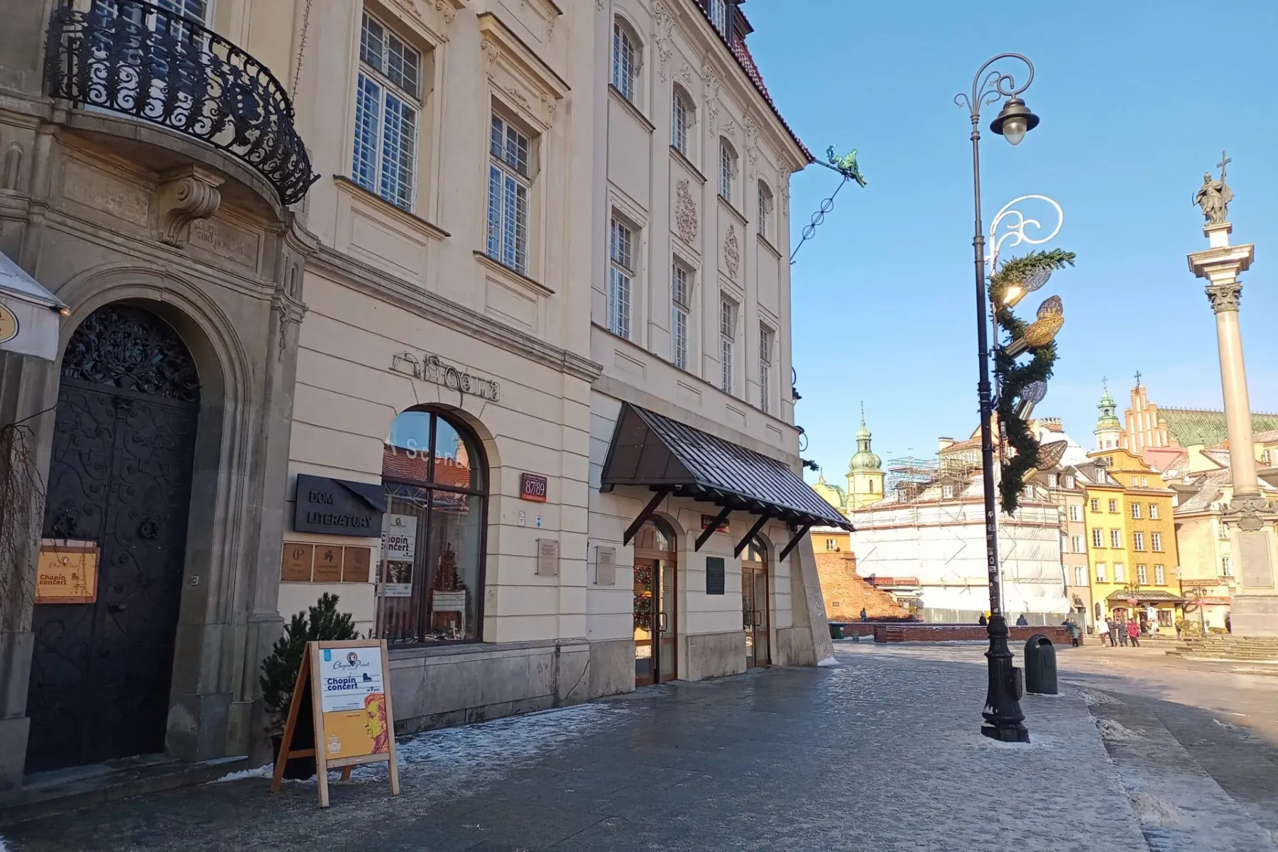 Fasada Domu Literatury i budynki na Starym Mieście w Warszawie, ze znakiem koncertu Chopina. Śnieżny chodnik.