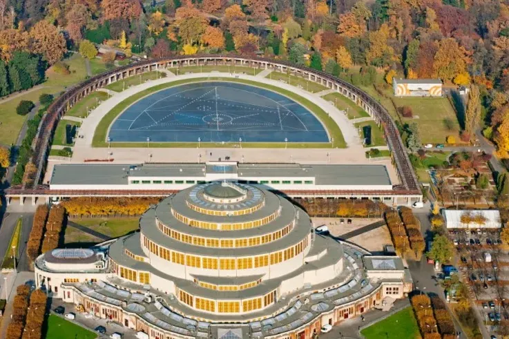 Aerial view of Centennial Hall in Wroclaw with its circular tiered roof, surrounded by the semicircular Pergola and autumn...