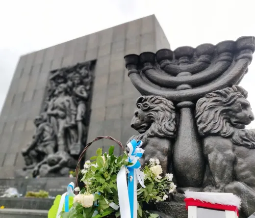 Pomnik Bohaterów Getta w Warszawie z menorą i kwiatami.