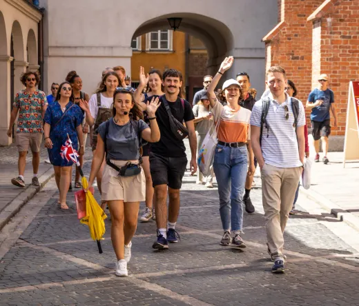 Szczęśliwi turyści na pieszej wycieczce z przewodnikiem po Starej Warszawie.
