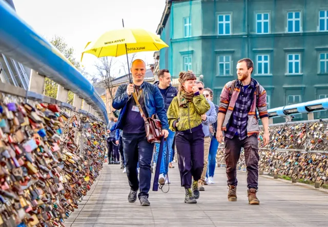 Un grupo de la excursión Walkative explora Cracovia, Polonia, caminando por un puente cubierto de candados de amor.