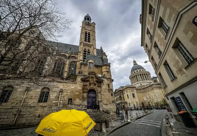 A yellow Walkative! umbrella in front of Saint-Germain-des-Prés church and the Panthéon in Paris.