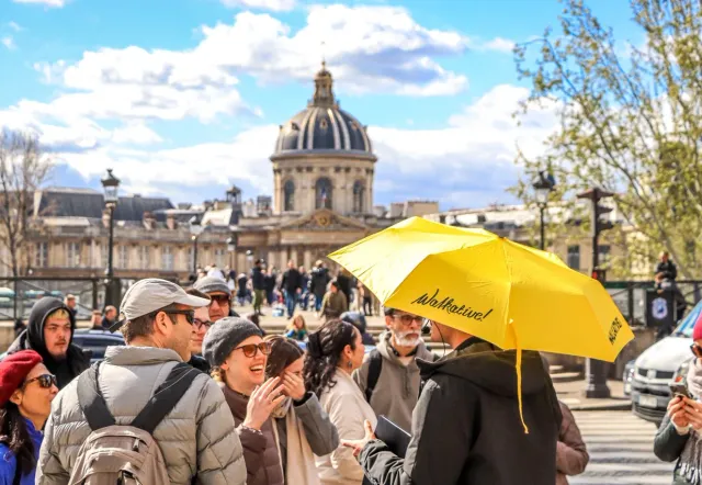 A Walkative! tour guide leads a group of happy tourists on a sunny day in Paris.