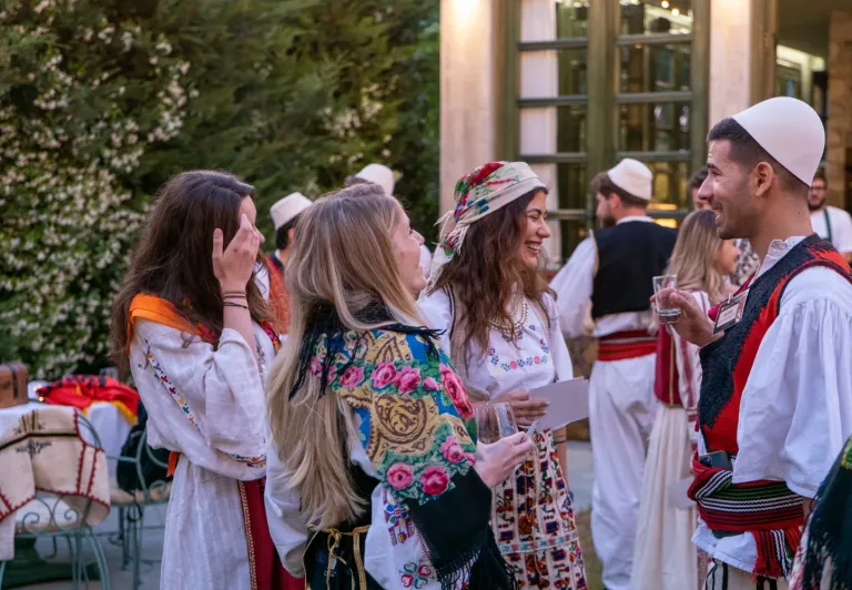 Touristen genießen eine albanische Nachtshow und interagieren mit Darstellern in traditioneller Kleidung.