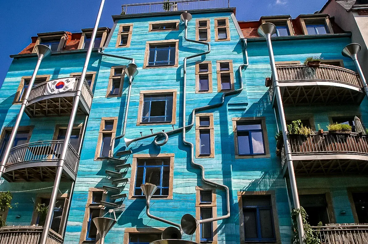 Blue building facade in Dresden with artistic downspouts and funnels, resembling musical instruments. A South Korean flag han