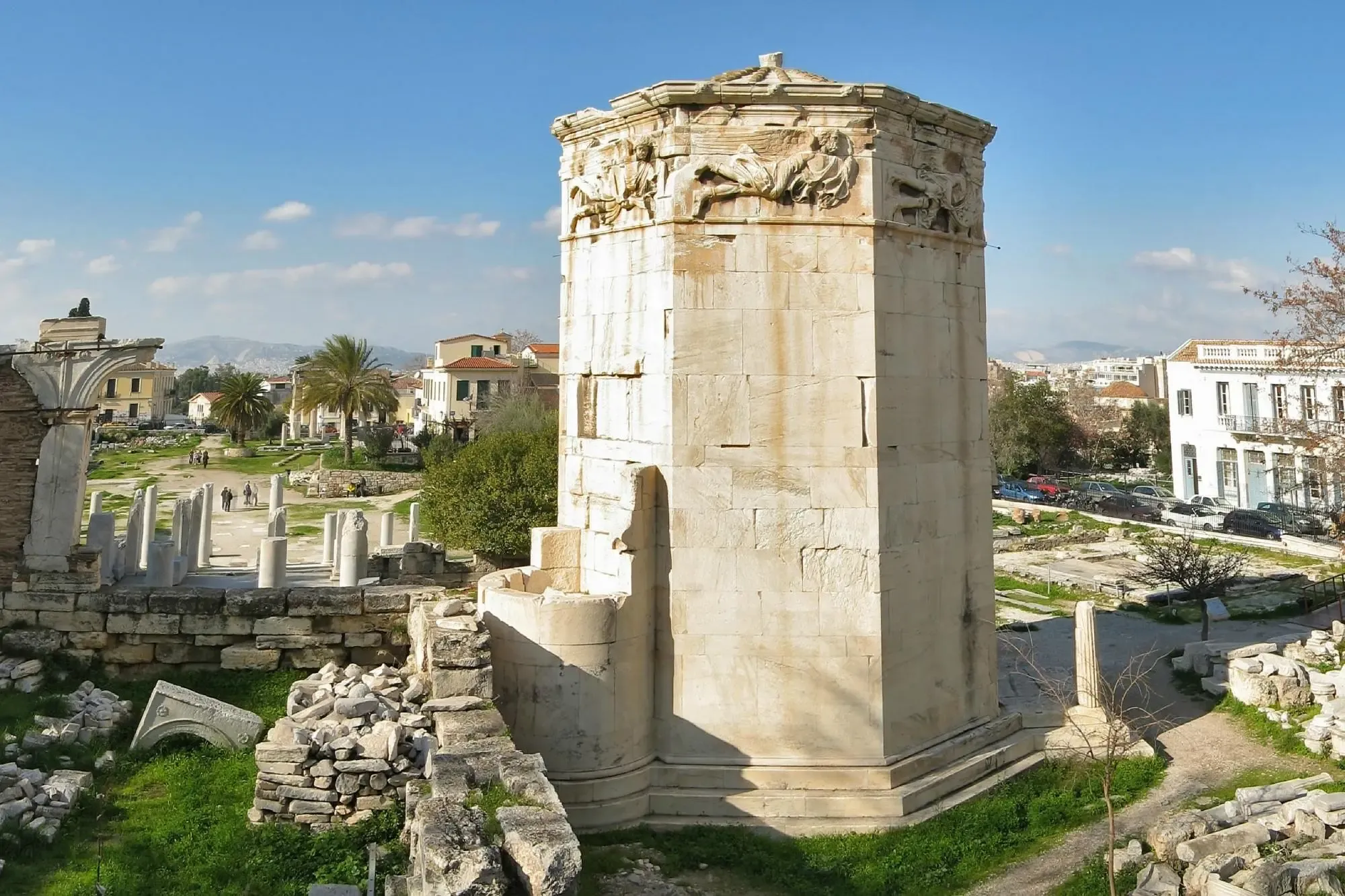 The octagonal Tower of the Winds stands amid the ruins of the Roman Agora in Athens on a clear, sunny day.