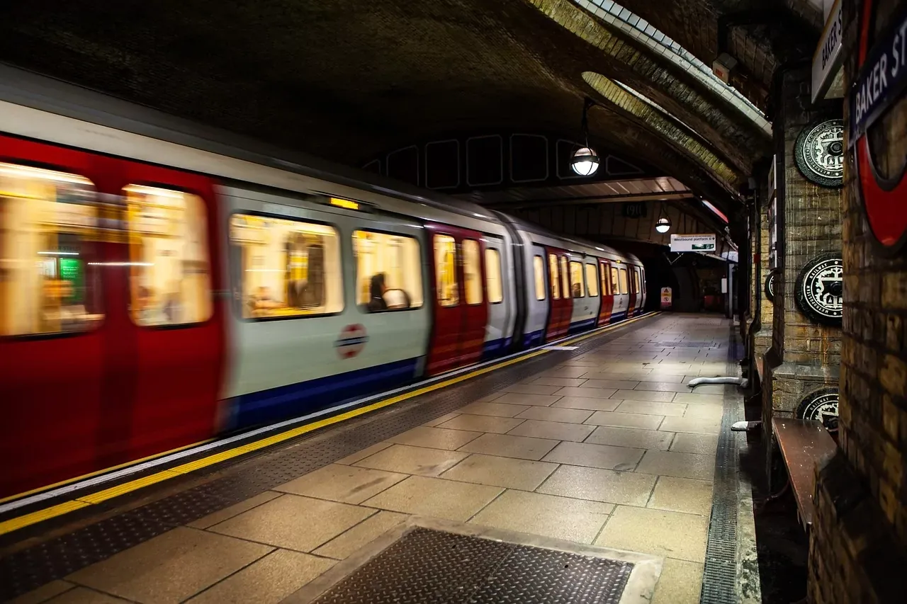 Pociąg metra londyńskiego z rozmytym ruchem wjeżdżający na peron stacji Baker Street z ceglanymi ścianami.