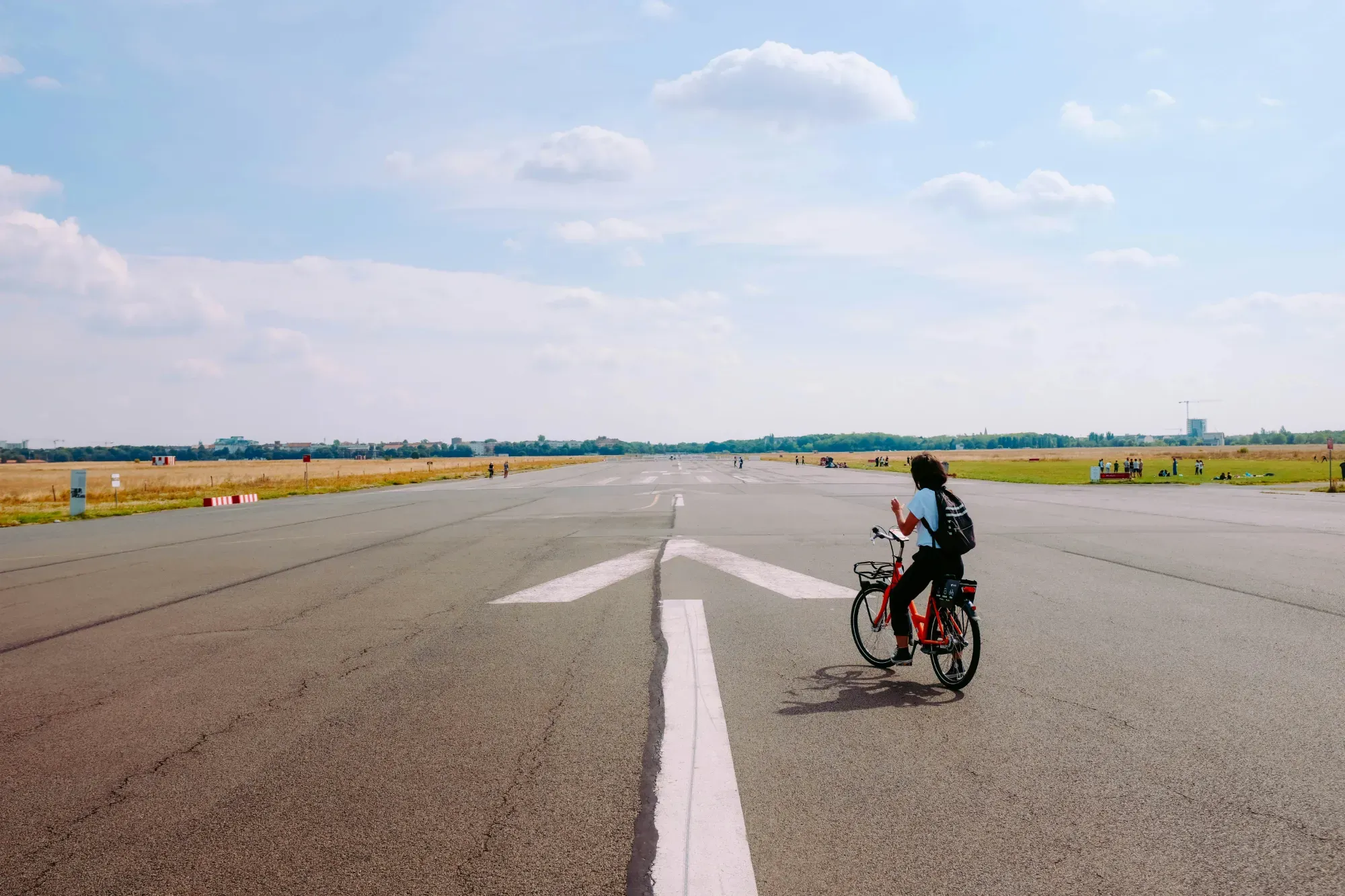 Una persona en bicicleta roja por la amplia pista de aterrizaje del Tempelhofer Feld en Berlín.
