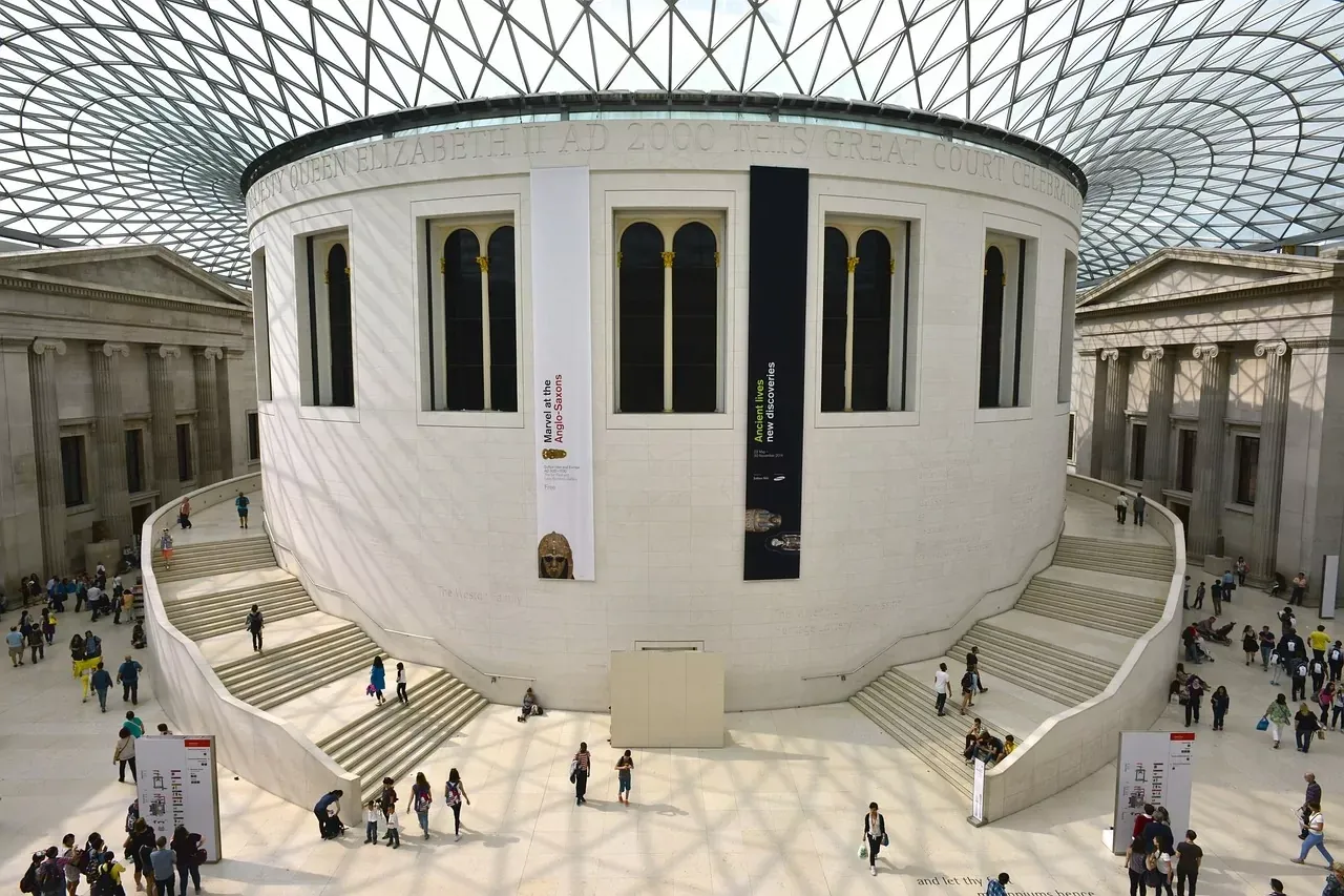 The interior of the British Museum's Great Court, featuring the circular Reading Room under a modern glass and steel roof, wi