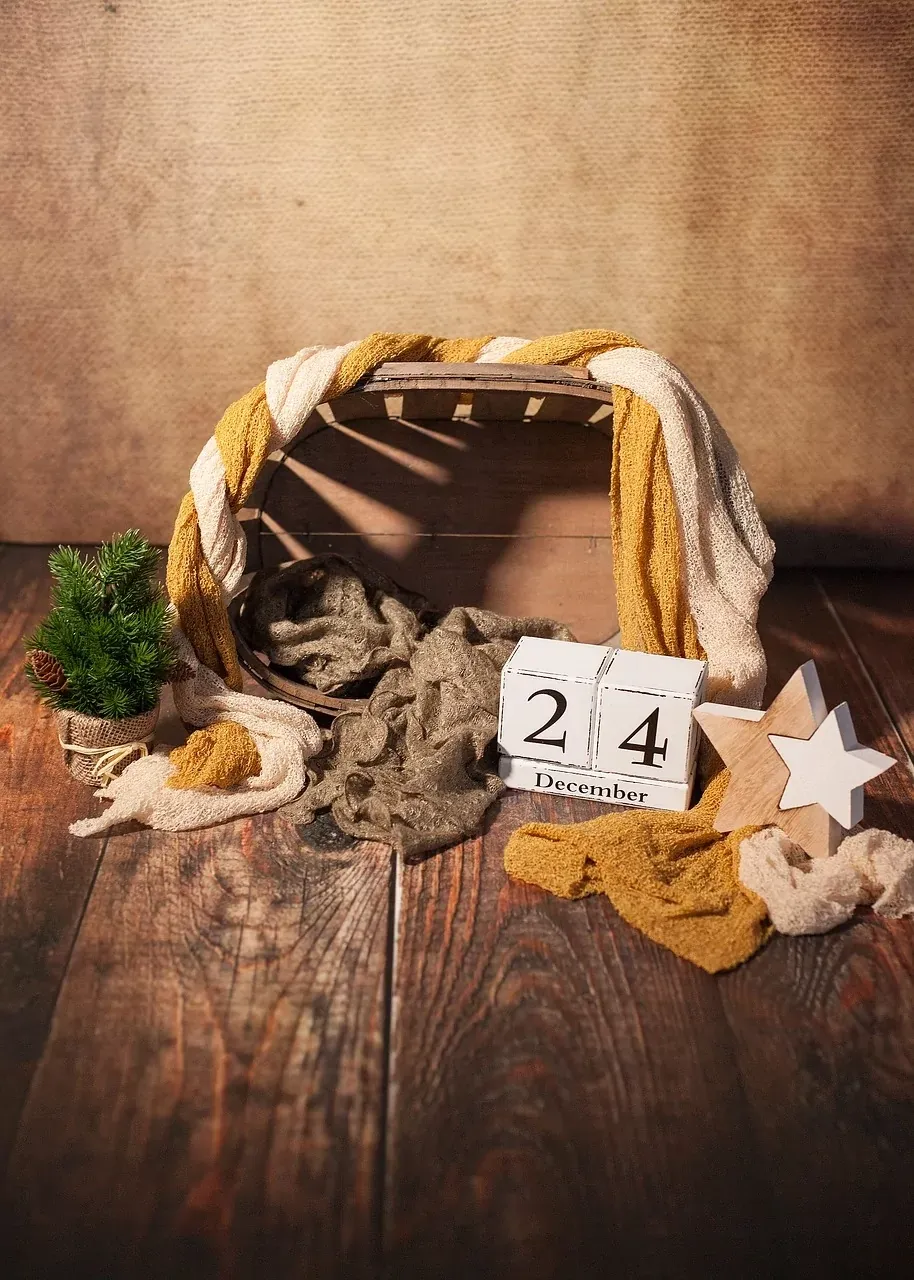 Rustic Christmas setup with wooden crate, draped fabrics, small evergreen tree, wooden star, and calendar showing 24 December