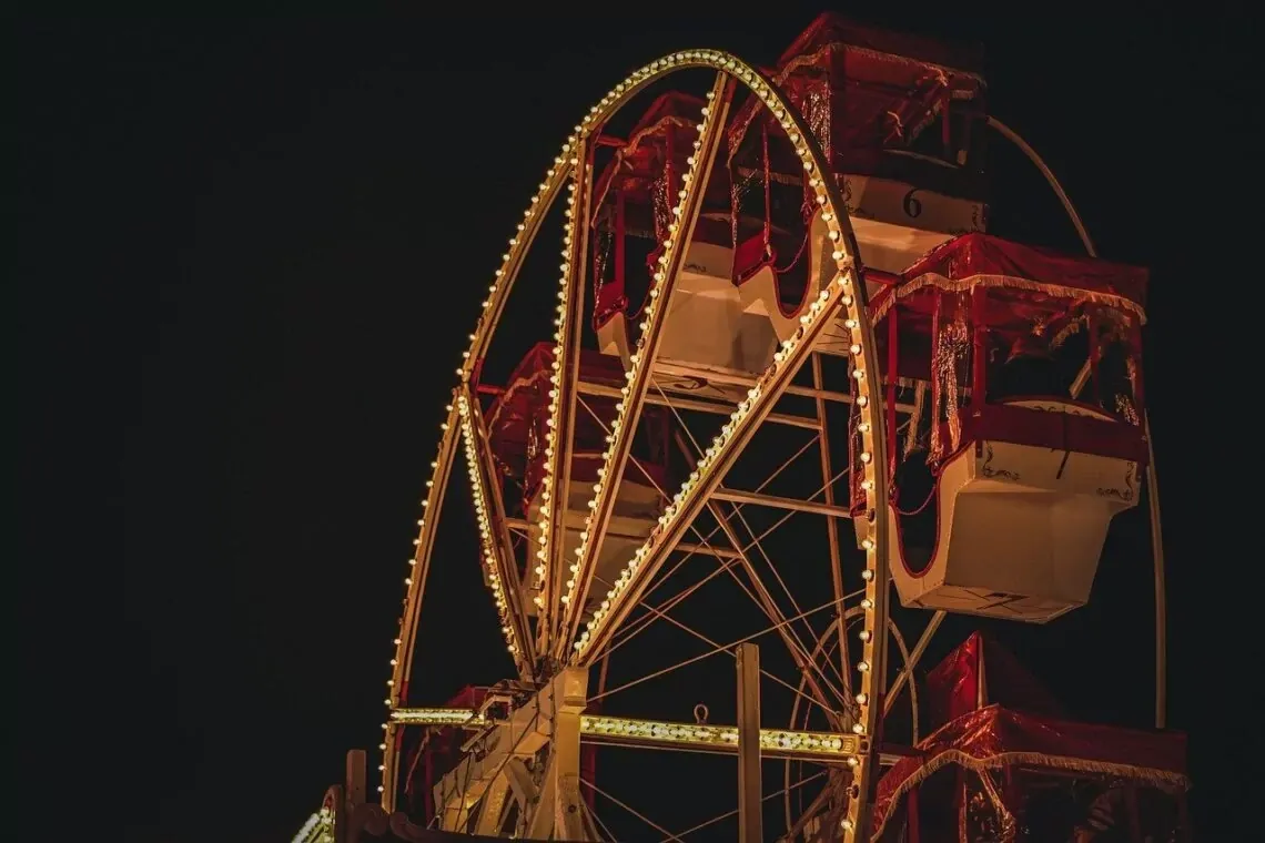 Illuminated Ferris wheel at a Christmas fair in Paris against the night sky.