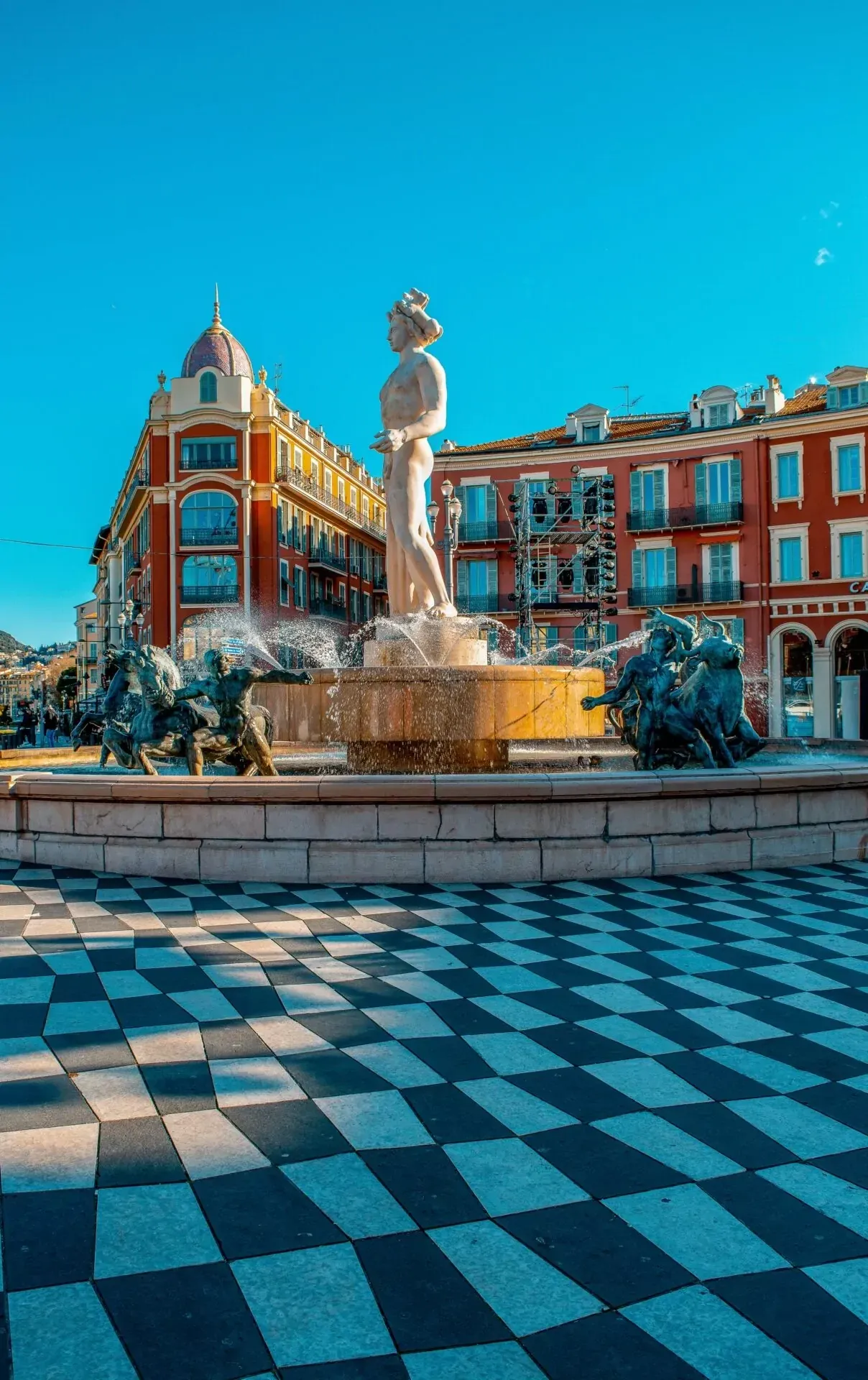 Fontaine du Soleil (Apollo-Brunnen) am Place Masséna in Nizza, mit Wasserspritzern und Schachbrettmuster-Pflaster.