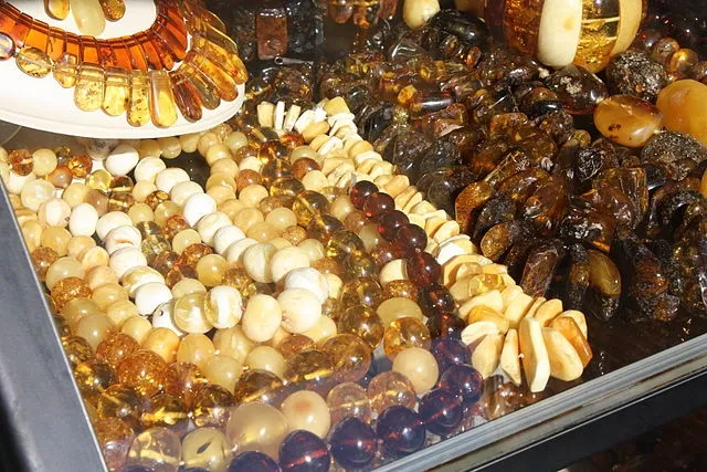 Auslage von Halsketten aus baltischem Bernstein in Farben wie Gold, Milchweiß und Dunkelbraun in einer Vitrine.