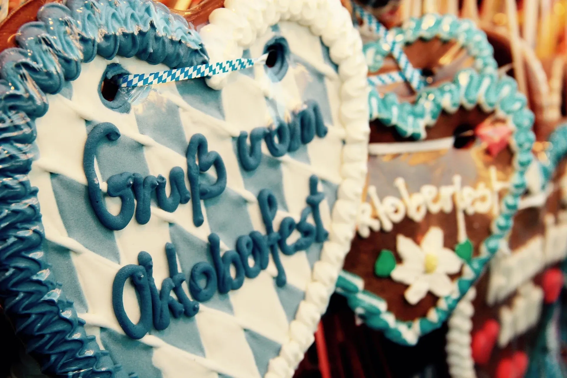A close-up of a gingerbread heart with "Gruß vom Oktoberfest" written in blue icing on a blue and white background.