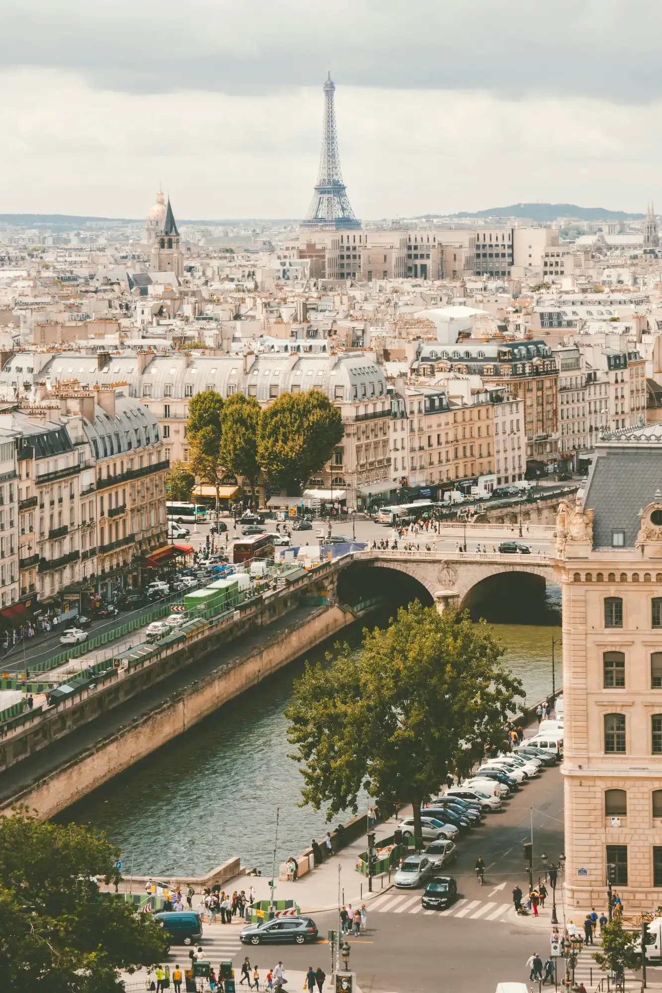 View over the Paris rooftops, the River Seine, and the Eiffel Tower in the distance on a cloudy day.