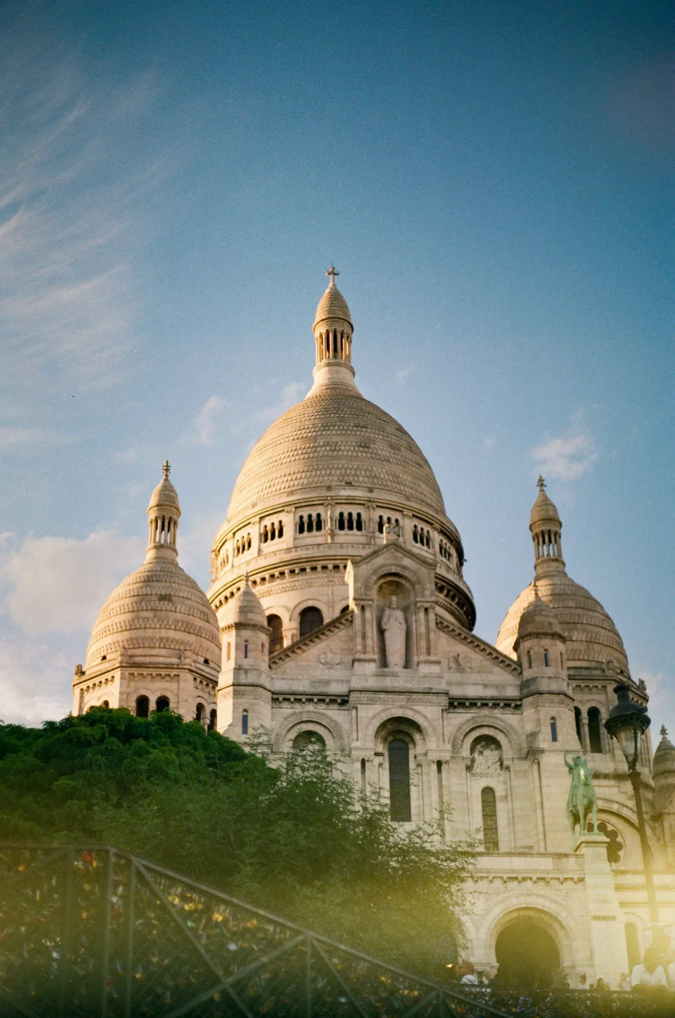 La basílica del Sacré-Cœur con sus cúpulas blancas y su fachada, vista desde abajo al atardecer.