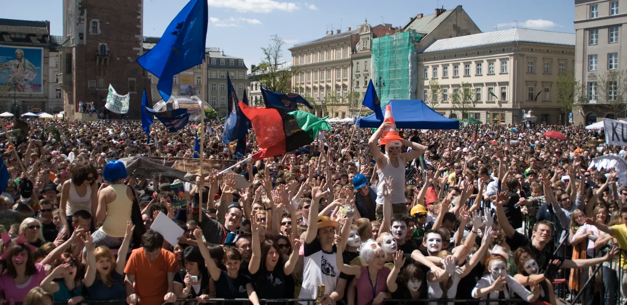 Ogromny tłum studentów świętujących na Rynku Głównym w Krakowie, z wieżą ratuszową w tle.