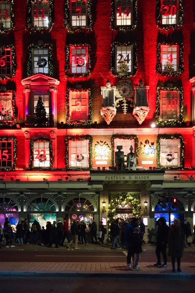 Exterior of Fortnum & Mason in London illuminated with red Christmas lights and decorated window displays during the festive