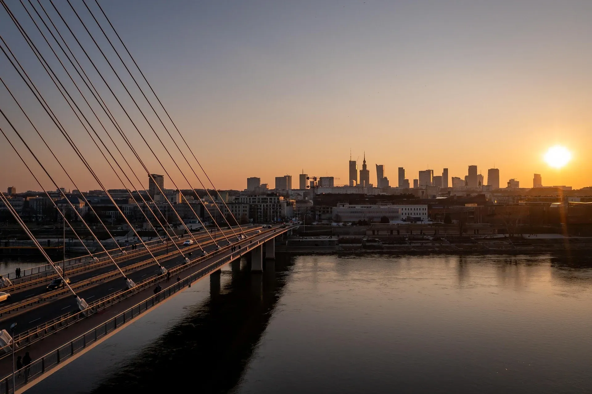 El Puente de Świętokrzyski sobre el río Vístula con el horizonte de Varsovia ante una puesta de sol dorada.