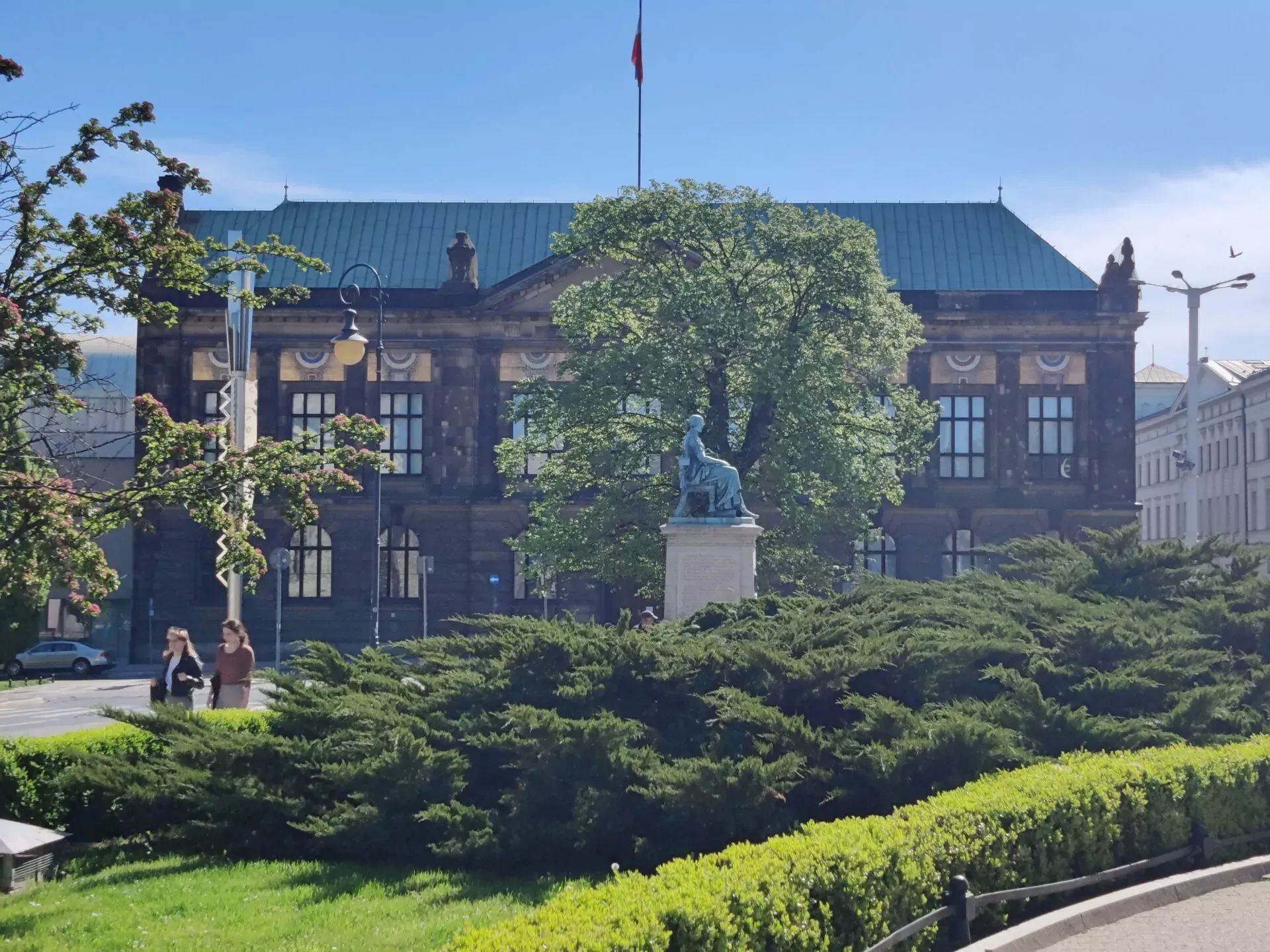 The National Museum in Poznan, a historic building, viewed from a park with a monument in the foreground.