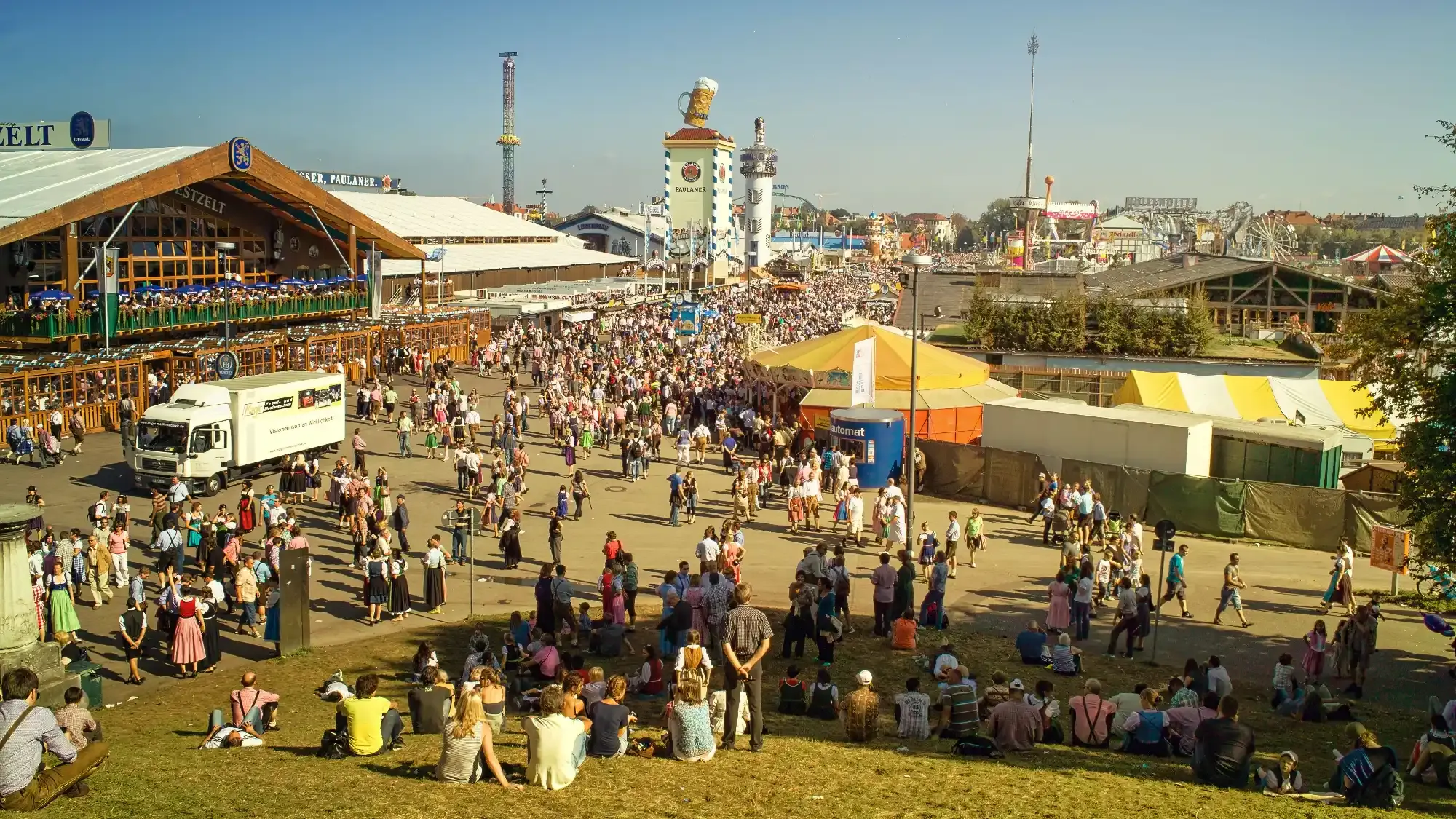 Słoneczny dzień na Oktoberfest w Monachium. Tłumy ludzi przechadzają się między namiotami piwnymi i straganami.