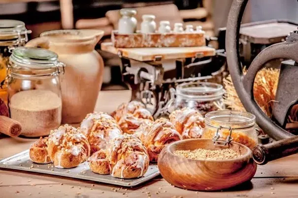 Traditional St. Martin's croissants with icing and nuts on a tray, displayed with baking ingredients and an antique scale.