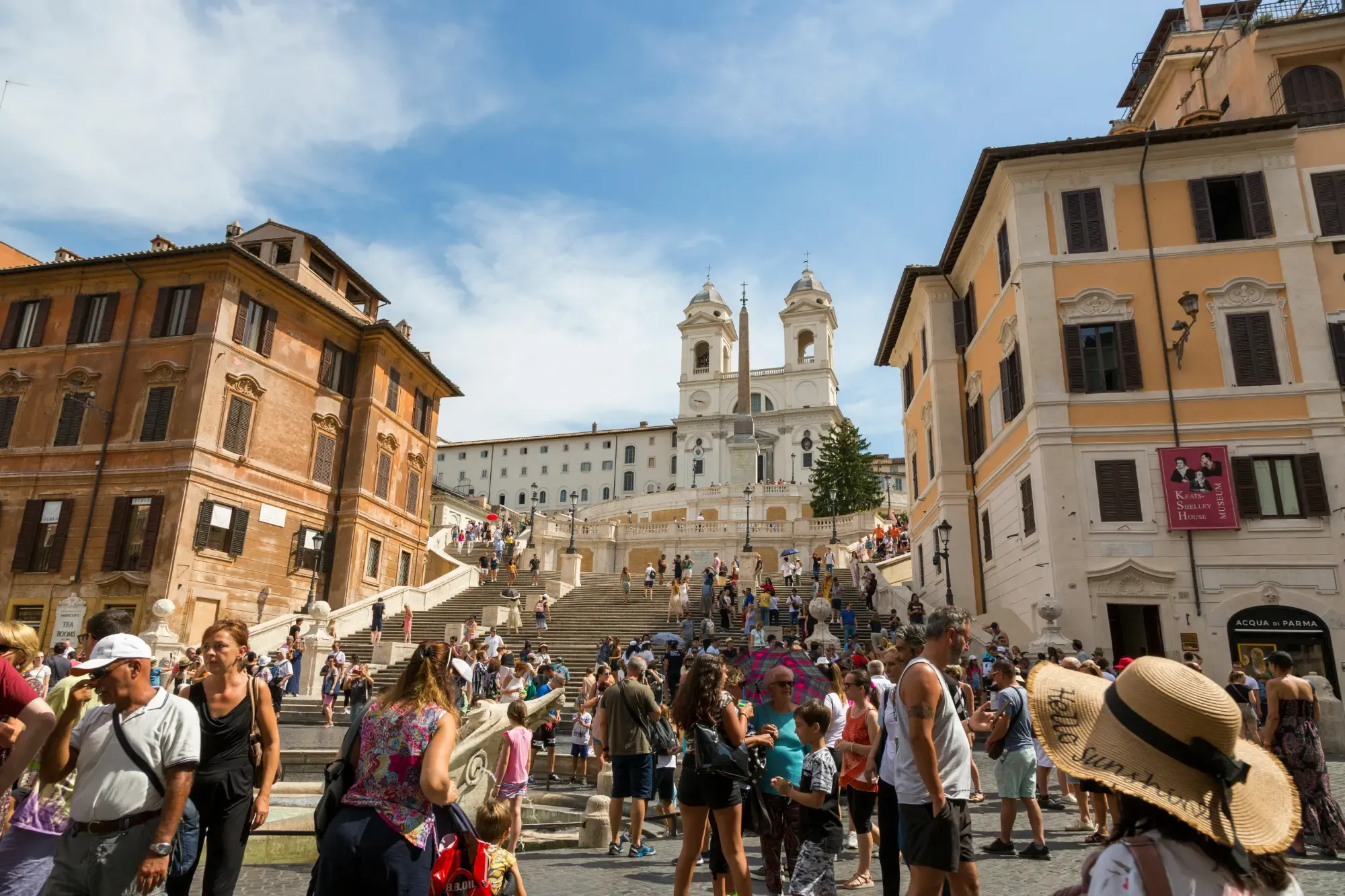 Numerosos turistas en la Escalinata de la Plaza de España en Roma, subiendo hacia la iglesia de Trinità dei Monti bajo un cie